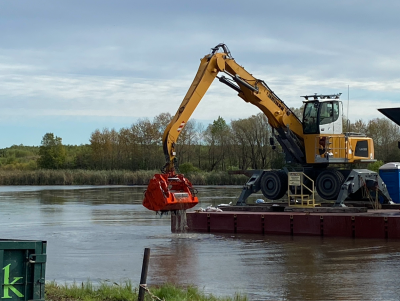 a backhoe on a barge dredges sediment