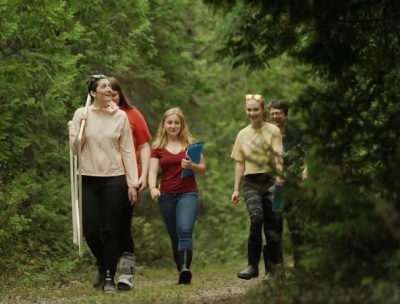 Michigan High School Students walk through Thomson's Harbor State Park carrying science equipment to collect data on plants in the park. (Credit: Great Lakes Outreach Media)