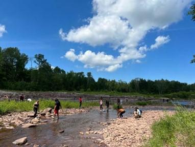 Students from the 2022 Learning from the Land Summer Youth Program explore rocks and water while learning about local geology at Bad River Falls.