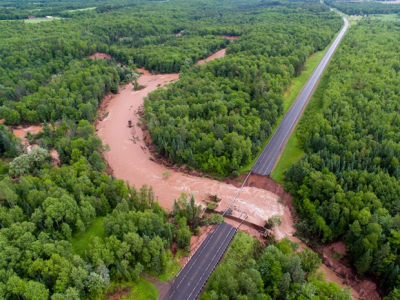 Fish Creek rages through a highway after washing out a bridge in the Father’s Day storm.