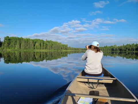 Person holding a camera on a boat for Loon Survey