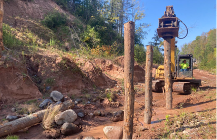Logs being emplaced vertically by machine operator.