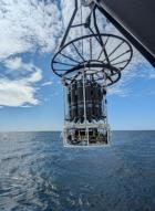 A rosette device hovering over a body of a water to collect water quality samples